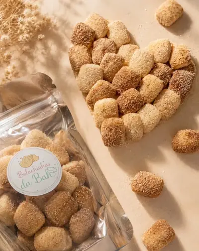 Bolachinhas de açúcar e canela arrumadas em formato de coração, ao lado de um pacotinho da Bolachinhas da Bah